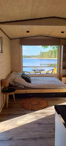 a bed in a room with a large window at BEJOT domki nad jeziorem in Wysoki Most