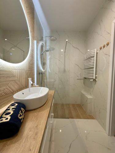 a white bathroom with a sink and a mirror at Apartament Boho Let's Sea Gąski in Gąski
