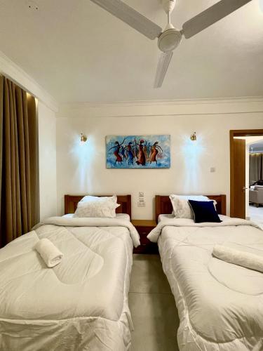 two beds in a room with a painting on the wall at Tulivu Beach Stays in Jeuri