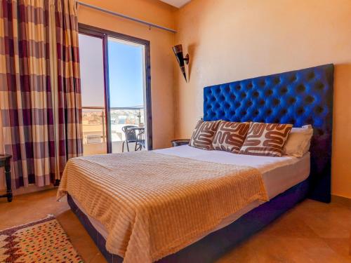 a bedroom with a bed with a blue headboard and a window at Beach Apartment with Pool Banana Beach Surf Spot in Aourir
