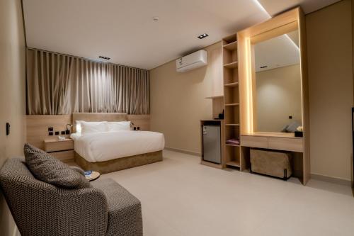 a hotel room with a bed and a chair and a mirror at Aurion AsSalaam Hotel Apartment in Medina