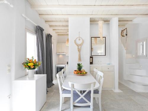 a white kitchen with a white table and chairs at Parfait Villa, Mykonos in Agios Ioannis Mykonos