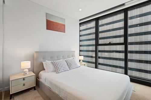a bedroom with a white bed and a large window at CBD Luxury River View & Fireworks 1Bed Apt The One in Brisbane