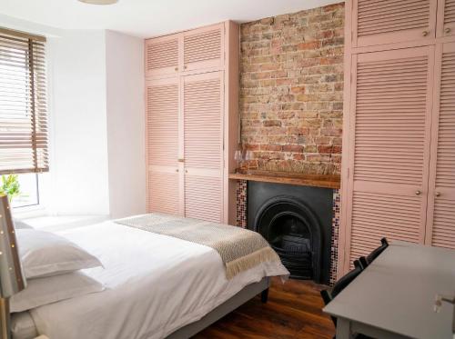 a bedroom with a brick wall and a bed and a fireplace at Sunny Homestay Room, 10 Mins North Laine, 6 Mins Station in Brighton & Hove