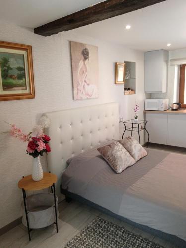 a bedroom with a bed and a vase of flowers at Passage des Romains studio in Horbourg