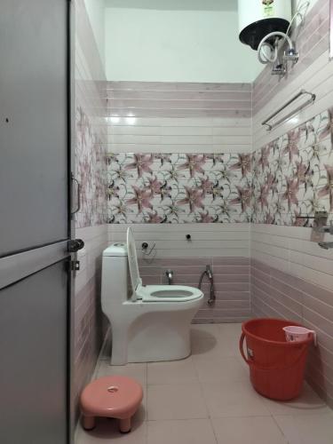 a bathroom with a toilet and a red bucket at Hotel Shri Yamuna Gaulok Dham in Kharsālī