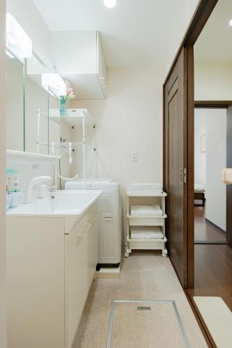 a white bathroom with a sink and a mirror at 逸泊居 in Osaka