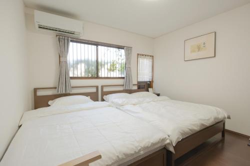 a bedroom with a bed with white sheets and a window at 逸泊居 in Osaka