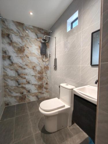 a bathroom with a white toilet and a sink at Rimba Inn in Kijal