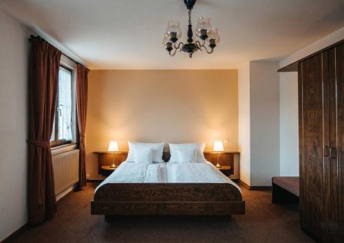 a bedroom with a bed with two lamps and a chandelier at Hotel & Restaurant Krone in Märkt in Weil am Rhein