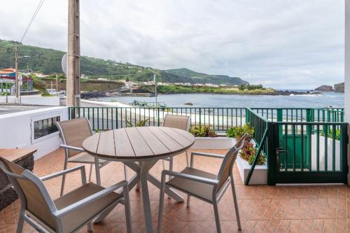a table and chairs on a balcony with a view of the water at Casas do Porto - Azalea and Hortênsia in Mosteiros