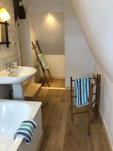 a bathroom with a sink and a tub and a chair at La Gruchette in Gruchet-Saint-Siméon