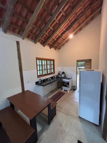 a kitchen with a table and a refrigerator at Casa na Mata - 2 min da Praia de fora com WiFi in Paraty