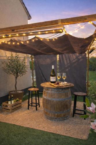 a wine bottle and glasses on a barrel under a tent at Roulotte insolite in Veaugues