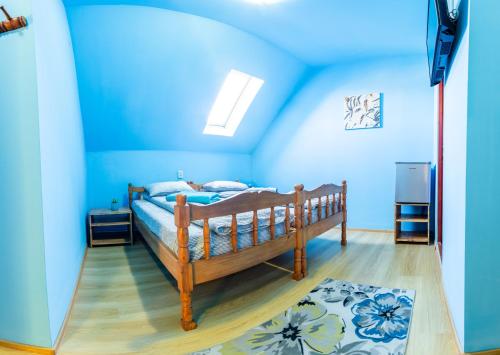 a bedroom with blue walls and a wooden bed at Írisz Vendégház in Lăzarea