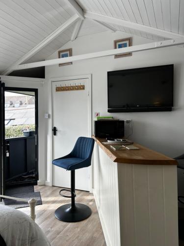 a room with a bar with a blue chair and a tv at Stylish Cabin in East Sussex near Newhaven ferry in Newhaven