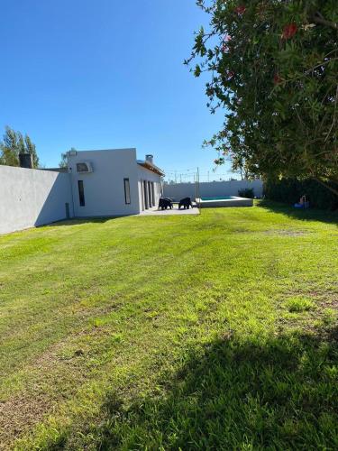 a grassy yard with a white building and a tree at Quinta Las Lilas in Chivilcoy