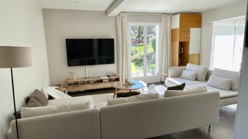 a living room with white furniture and a flat screen tv at Rivéa Bizy - Villa 150m2 - 2ou5 CH - 2 SDB - Parking Wifi in Vernon