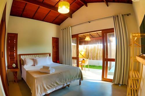 a bedroom with a bed and a sliding glass door at Maysu Patacho Chalé Piscina Privativa in Pôrto de Pedras