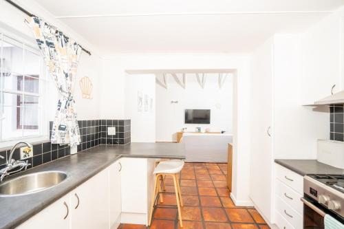 a white kitchen with a sink and a counter at Benguela Cottage in Langebaan