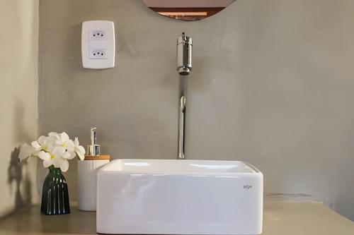 a sink in a room with a vase of flowers at Maysu Patacho Chalé Piscina Privativa in Pôrto de Pedras