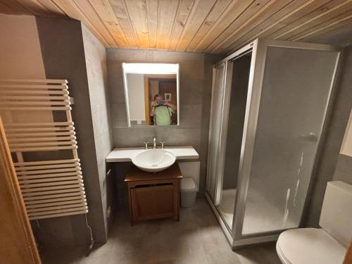 a man taking a picture of a bathroom with a sink and shower at Le Vieux Chalet in Gstaad