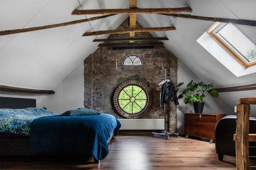 a attic bedroom with a bed and a window at Bed and Breakfast Lovenem - ruime studio met zwembad en sauna op de Veluwe in Leuvenheim