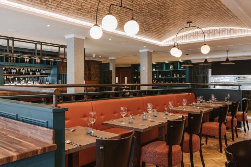a restaurant with wooden tables and chairs and lights at The Malone Hotel in Belfast