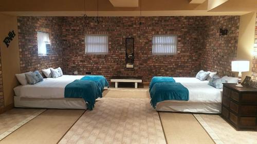 a bedroom with two beds and a brick wall at Dolphin Villa in Gqeberha
