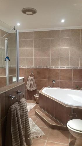 a bathroom with a tub and a toilet and a sink at Dolphin Villa in Gqeberha
