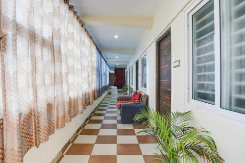 a hallway with a checkered floor and two chairs at Hotel O Aqua Comforts in Yelahanka