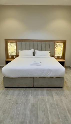 a bedroom with a large white bed with wooden floors at Alturya in Al-ʿUla