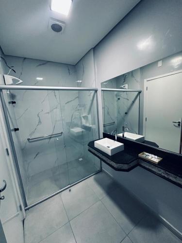 a bathroom with a glass shower and two sinks at Charles Hotel in Pôrto Ferreira