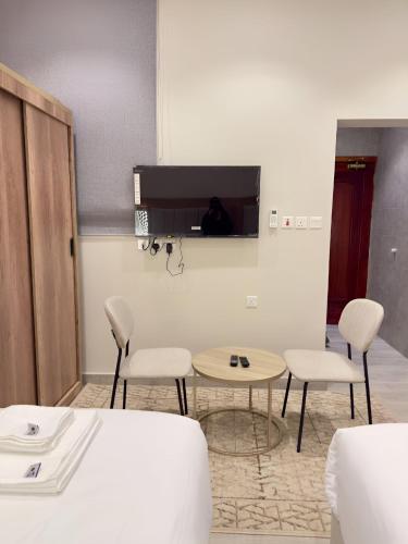 a room with two chairs and a table and a tv at Alturya in Al-ʿUla