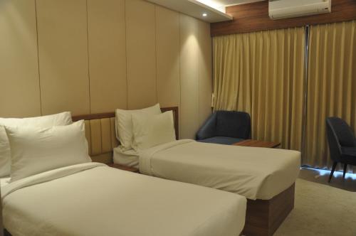 a hotel room with two beds and a chair at Pahadi Convention in Rourkela