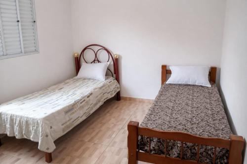 two beds in a room with white walls and wooden floors at Casa independente e espaçosa em Poços de caldas in Poços de Caldas