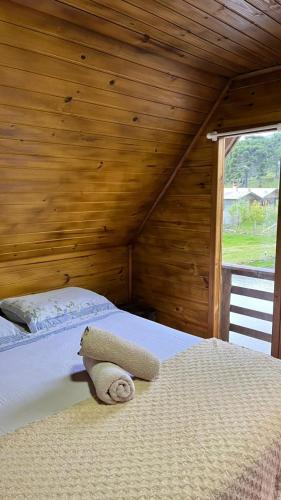 a bedroom with a bed with a wooden wall at Chalé do Lago - Refúgio Arara Azul in Urubici