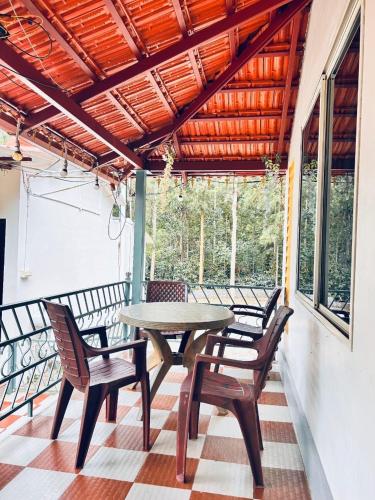a patio with a table and chairs on a porch at Malnad Mist in Attigundi