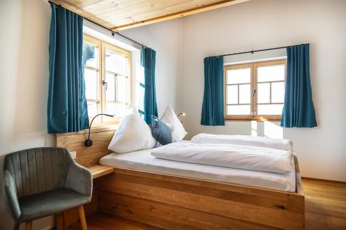 a bedroom with a bed with blue curtains and a chair at Chalet Zaferna in Mittelberg