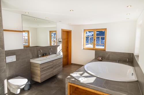 a bathroom with a tub and a sink and a toilet at Chalet Zaferna in Mittelberg