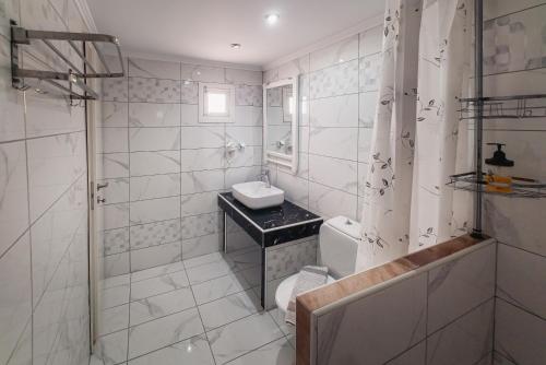 a white bathroom with a sink and a shower at Cloud9 Hotel Shisha & Cocktail Bar - Adults Only in Malia