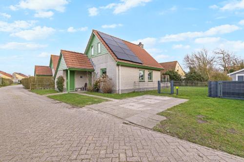a green and white house with a red roof at Vakantiehuis Miriam op park Strandslag Julianadorp aan Zee in Julianadorp