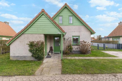 a green and white house with a green door at Vakantiehuis Miriam op park Strandslag Julianadorp aan Zee in Julianadorp