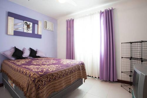 1 dormitorio con 1 cama con paredes de color púrpura y ventana en Apto Cabo Frio Marina Clube, en Cabo Frío