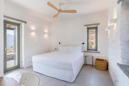 a white bedroom with a bed and a ceiling fan at Lithi House in Grionísi
