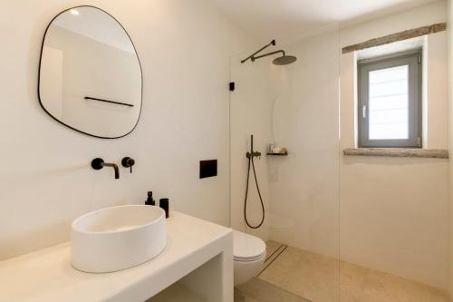 a white bathroom with a sink and a mirror at Lithi House in Grionísi