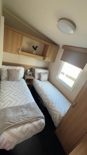 two beds in a small room with a window at 107 Arran View with WiFi in Ayr