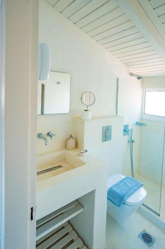 a white bathroom with a toilet and a sink at Irini's Bayside Loft in Fiskardo