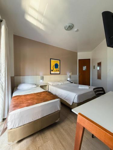 a hotel room with two beds and a television at Pousada Villa Atlântica in Balneário Camboriú