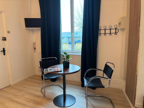 a table and two chairs in a room with a window at Le refuge in Bellême
